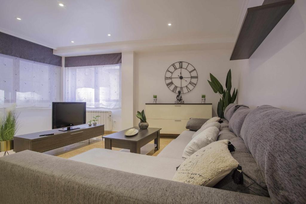 ein Wohnzimmer mit einem Sofa und einem TV in der Unterkunft Apartamento en Raxó in Pontevedra