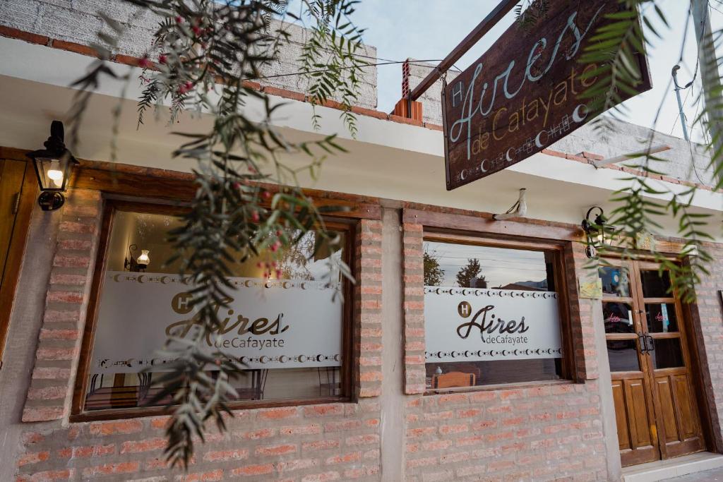 a brick building with two windows and a sign at Aires de Cafayate in Cafayate