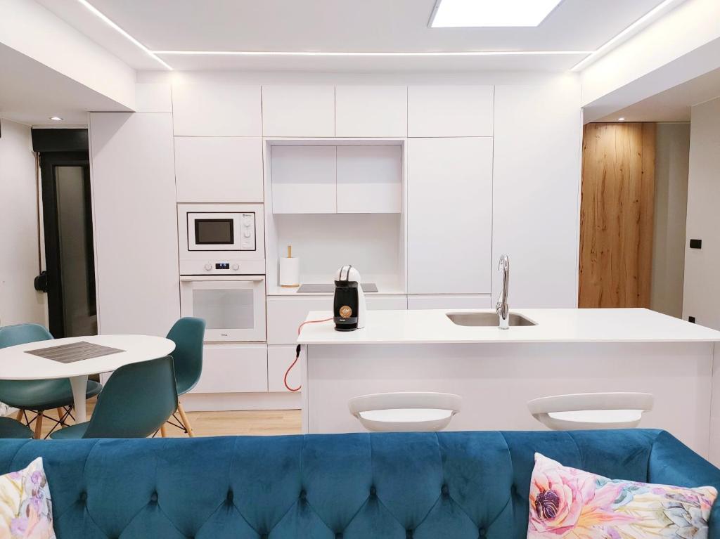 eine Küche und ein Wohnzimmer mit einem blauen Sofa in der Unterkunft OVIEDO CENTRO SANTA CLARA PISO DE LUJO in Oviedo