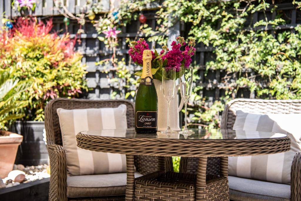 a table with a bottle of wine and flowers on it at The Garden Apartment in Deal