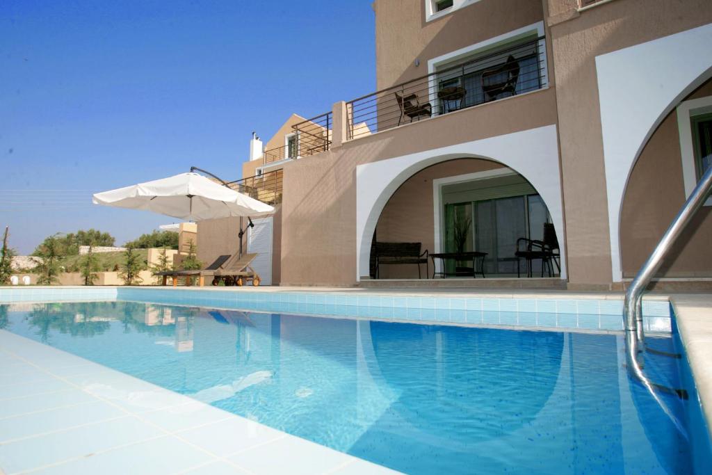 una piscina frente a una casa con sombrilla en Erofili Villas, en Lourdata
