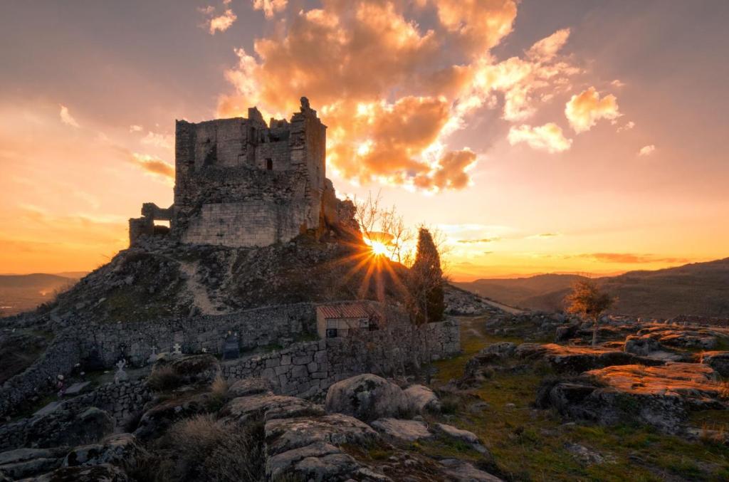 un antiguo castillo en la cima de una colina al atardecer en Restaurante & Hotel Rural El Mirador de Trevejo en Villamiel