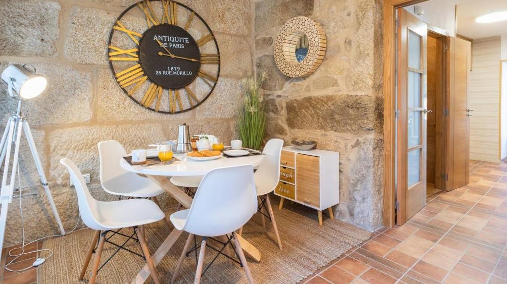 une salle à manger avec une table, des chaises et une horloge dans l'établissement Casa Angelita terraza con hórreo y barbacoa, à Poio