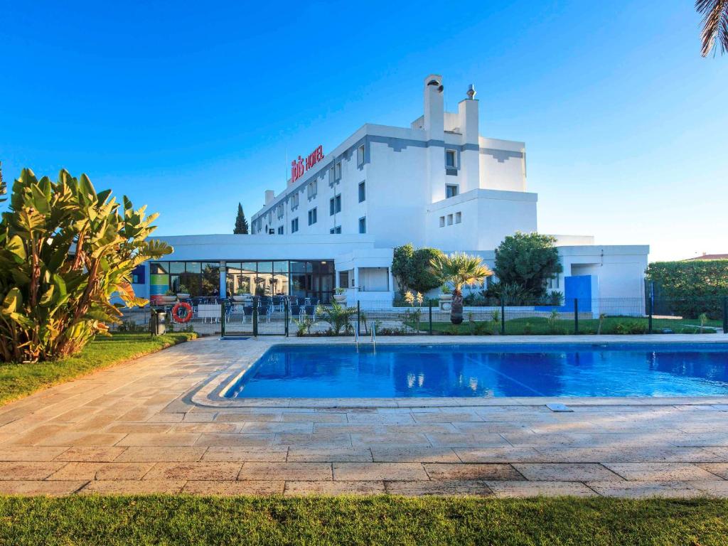 um hotel com piscina em frente a um edifício em Hotel ibis Faro Algarve em Faro