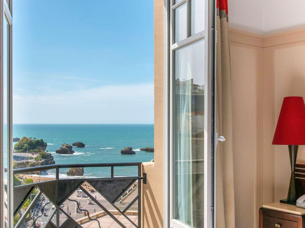 a room with a balcony with a view of the ocean at Mercure Plaza Biarritz Centre in Biarritz