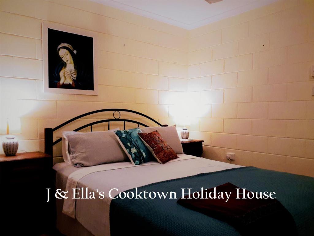 1 dormitorio con 1 cama y una pintura en la pared en J & Ella's Holiday House - 2 Bedroom Stays en Cooktown