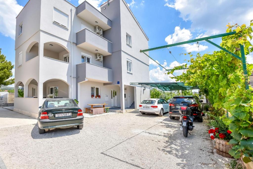 un bâtiment avec des voitures garées dans un parking dans l'établissement Apartments Juro, à Rogoznica