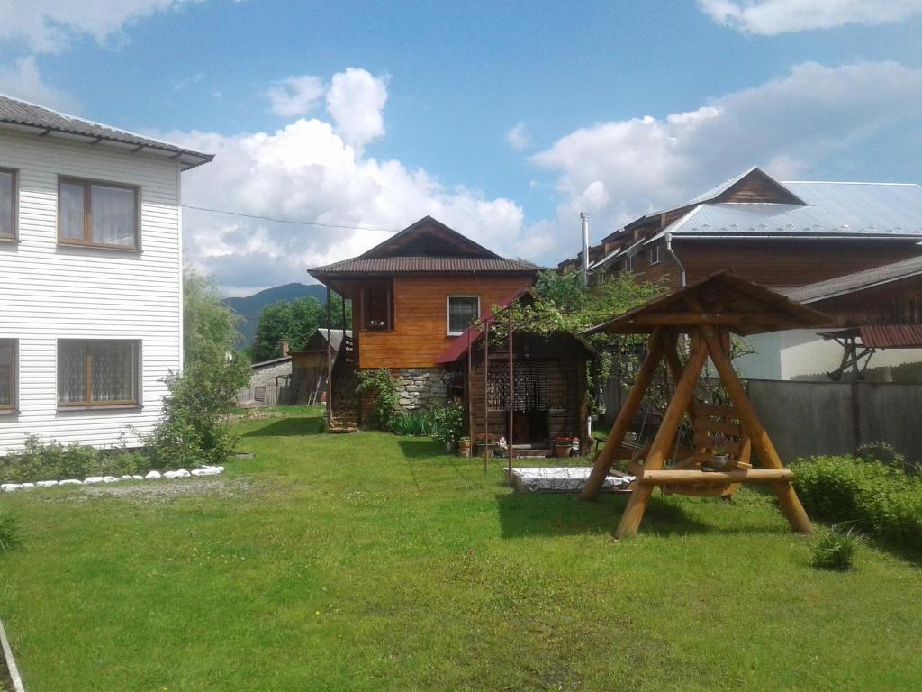 a yard with a house and a wooden structure at Міні Котедж in Verkhovyna