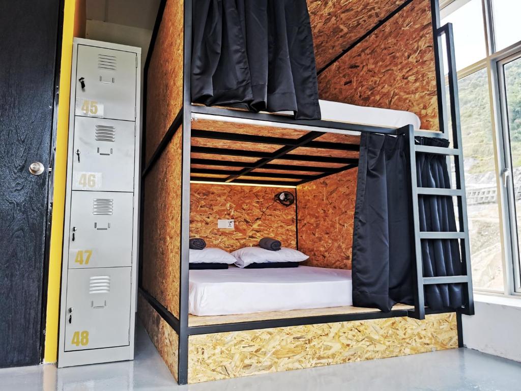 a room with a bunk bed in a brick wall at The Cocoon Capsule Hotel in Cameron Highlands