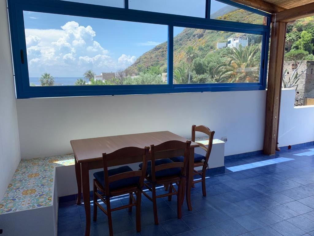 une table et des chaises dans une chambre avec une grande fenêtre dans l'établissement Il Vulcano a Piedi, à Stromboli