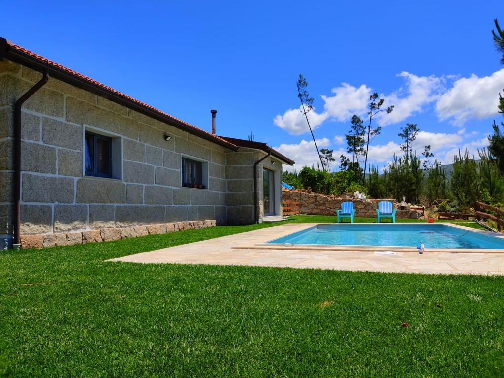 a swimming pool with two chairs in front of a house at Casa do Vale - Casa da Montanha - Gerês in Geres