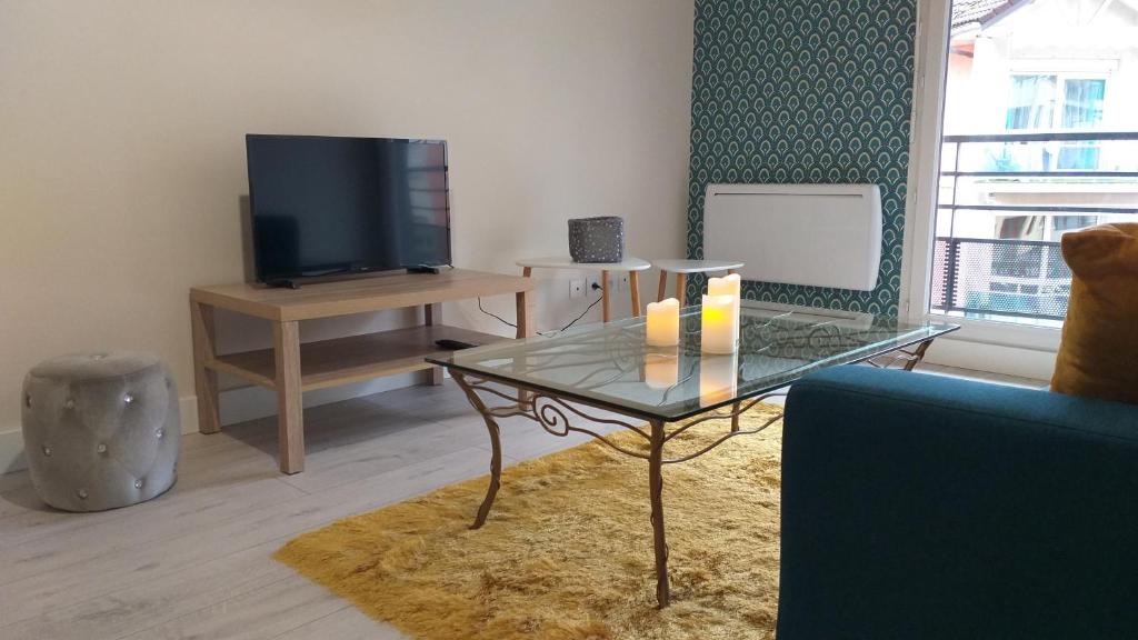 a living room with a glass table and a tv at Le Georges Marin in Bellegarde-sur-Valserine