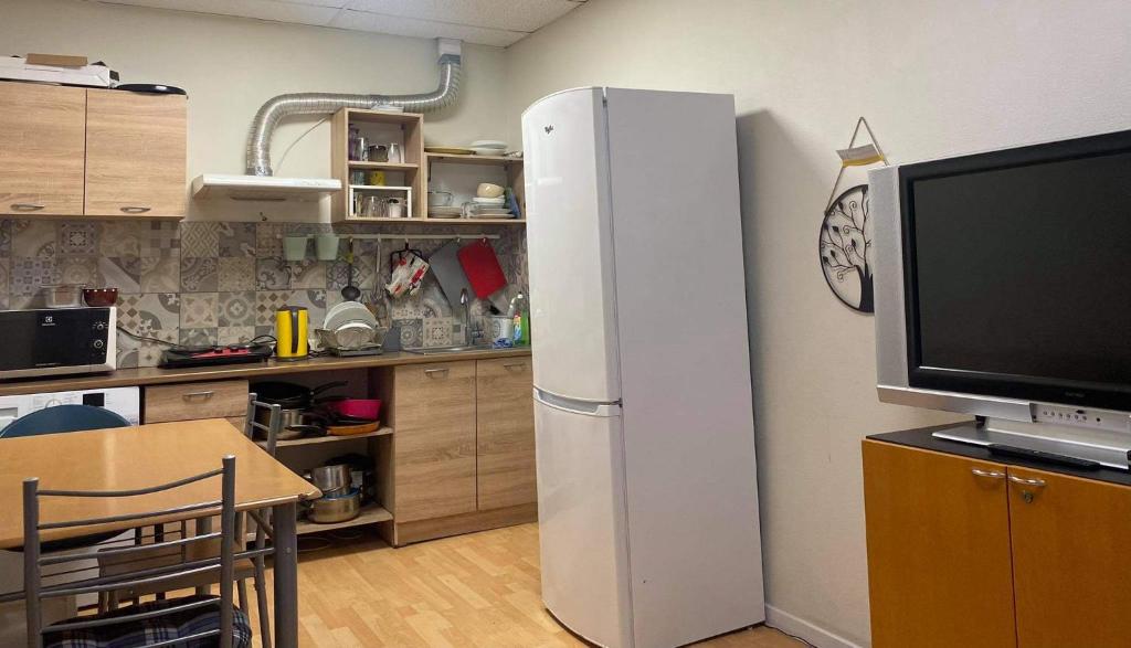 a kitchen with a refrigerator and a table and a tv at Hostel Umbrella in Tallinn