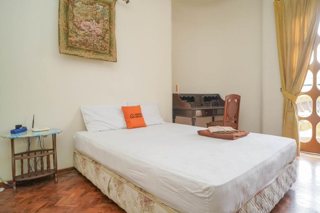 um quarto com uma cama com uma almofada laranja em KoolKost Syariah near Senayan City em Jakarta