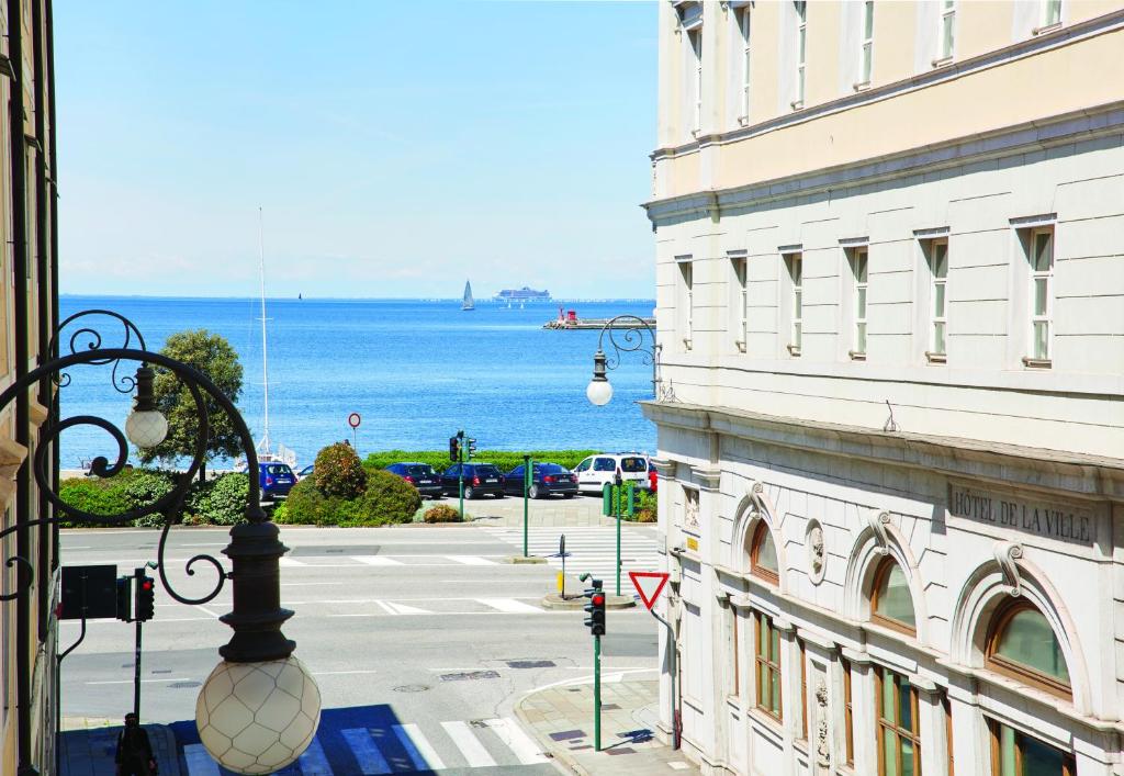 Blick auf eine Straße und das Meer von einem Gebäude in der Unterkunft YouMe Design Place Hotel in Triest