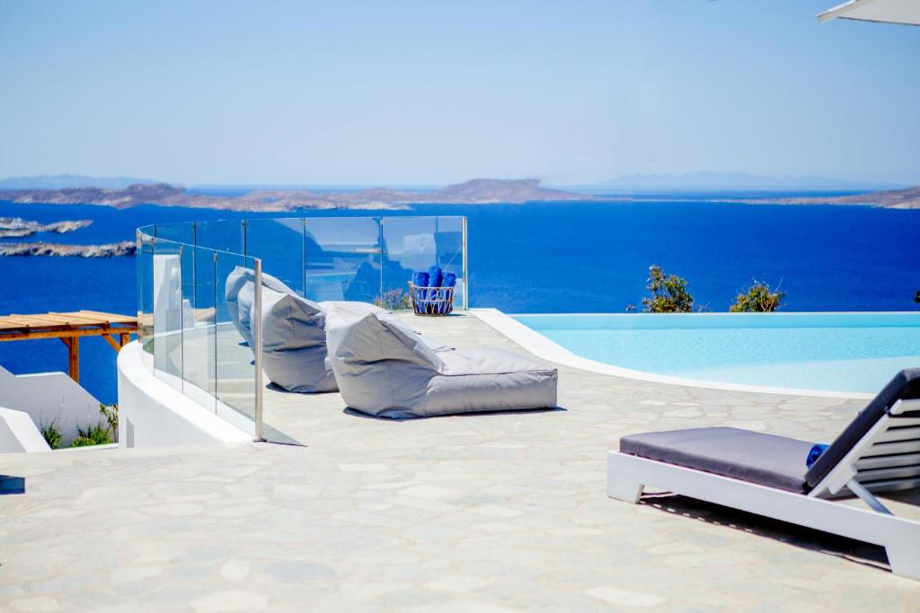 eine Terrasse mit einem Pool und Stühlen am Wasser in der Unterkunft Agnandi Cielo in Tourlos