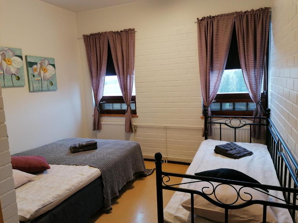 two beds in a room with two windows at Kaidanojan Kartano in Uusikartano