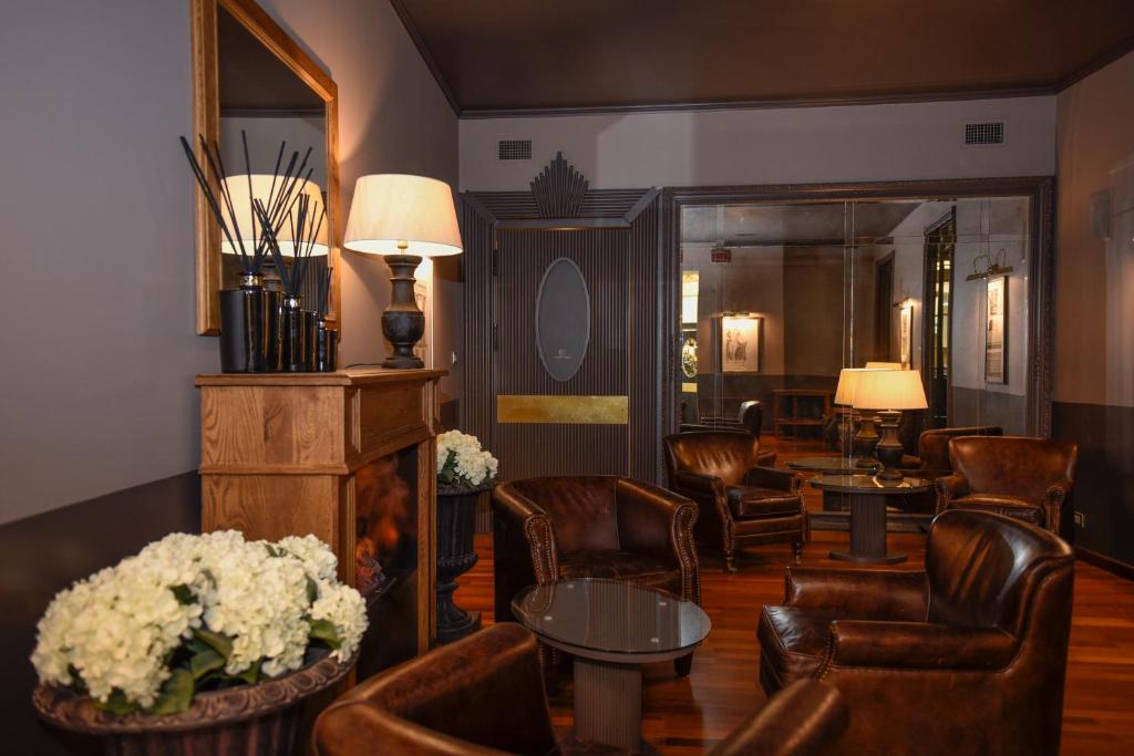 hol ze skórzanymi krzesłami, stołami i kwiatami w obiekcie The Tuscanian Hotel w Lukce