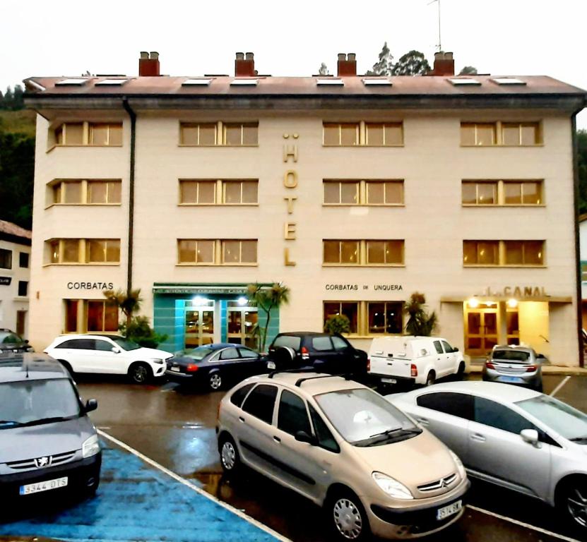 un estacionamiento con autos estacionados frente a un edificio en Hotel Canal, en Unquera