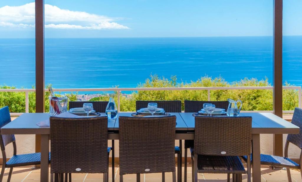 een eetkamer met een tafel en stoelen en de oceaan bij HomeHolidaysRentals Malvina in Pineda de Mar