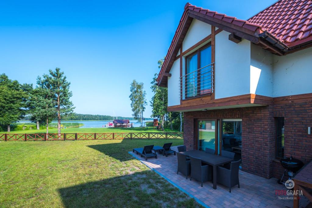 ein Haus mit einer Terrasse mit einem Tisch und Stühlen in der Unterkunft Rydzewo domek w zabudowie szeregowej nad jeziorem in Rydzewo