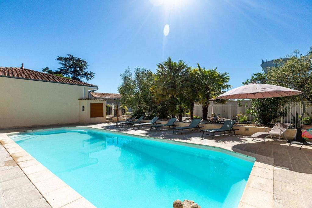 una piscina con sillas y sombrilla en Logis Hôtel L'Oliveraie, en Cognac