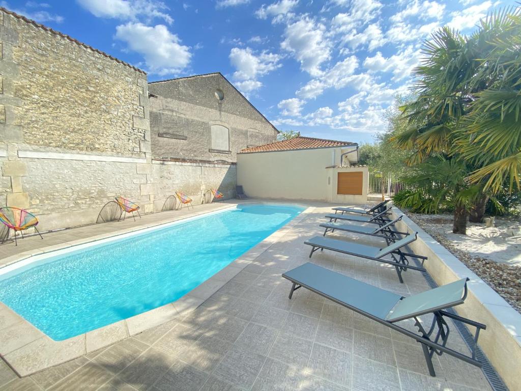 a swimming pool with lounge chairs next to a building at Logis Hôtel L'Oliveraie in Cognac