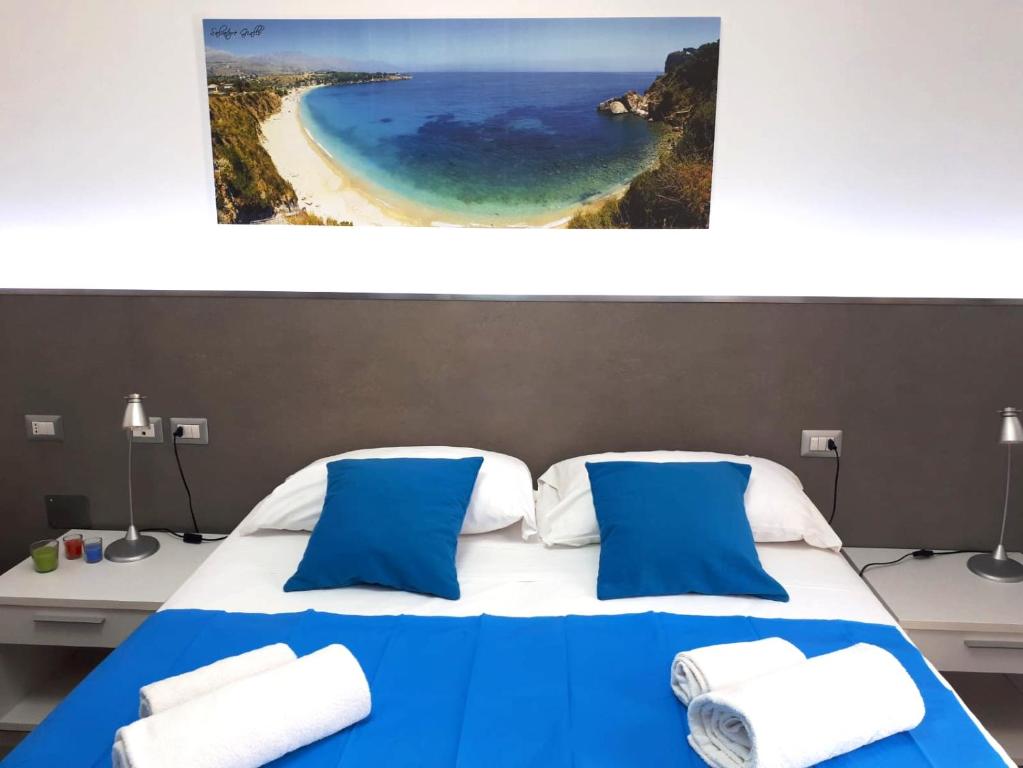 sypialnia z niebiesko-białym łóżkiem i plażą w obiekcie Le Camere del Crimiso w mieście Castellammare del Golfo