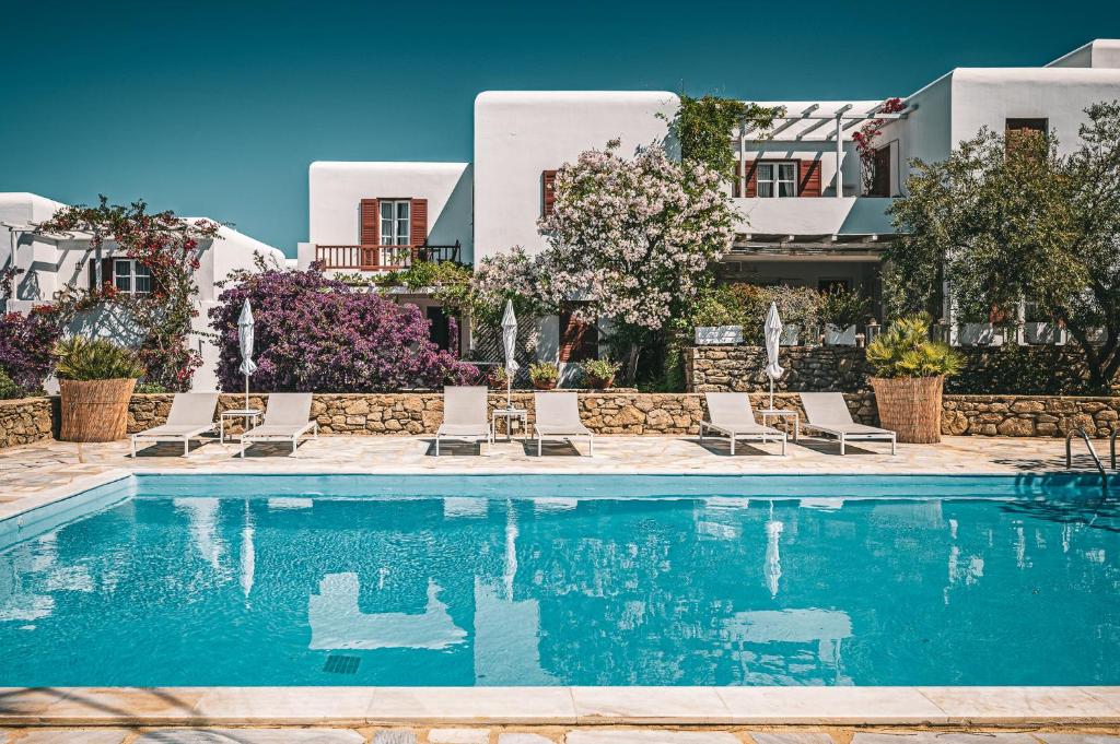 a swimming pool with chairs and buildings in the background at Casa Cozy in M&yacute;konos City