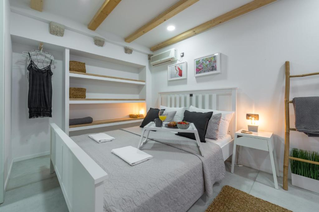 a white bedroom with a bed and a table at Apartments Bobo in Dubrovnik