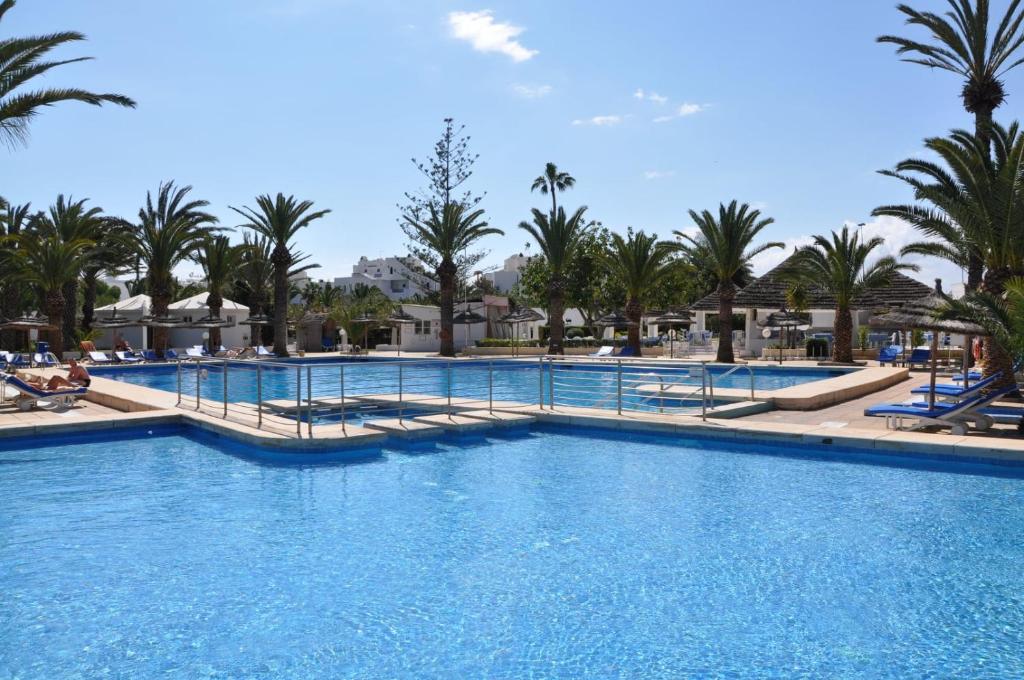 una piscina en un complejo con palmeras en Kanta Resort and Spa, en Sousse