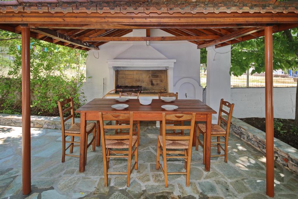drewniany stół i krzesła na patio z kominkiem w obiekcie The Akri House Agnondas w mieście Agnontas