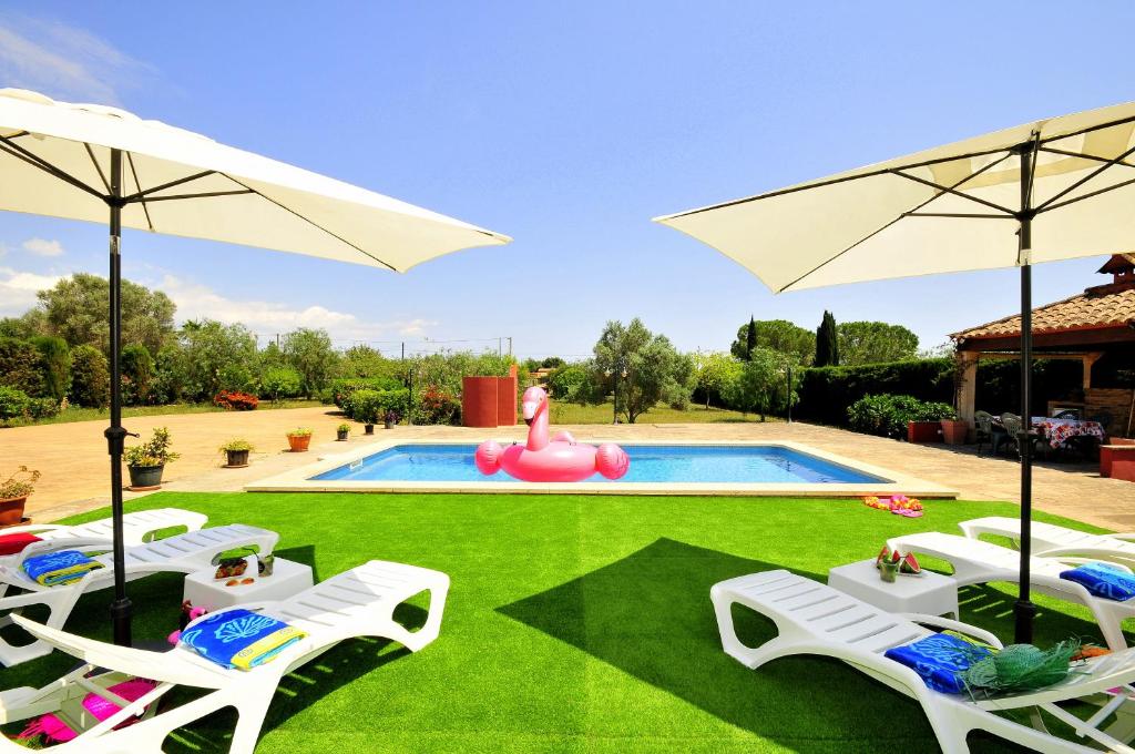 a group of lawn chairs and a pool with a pink inflatable at Villa Mallorca Paradise in Llucmajor