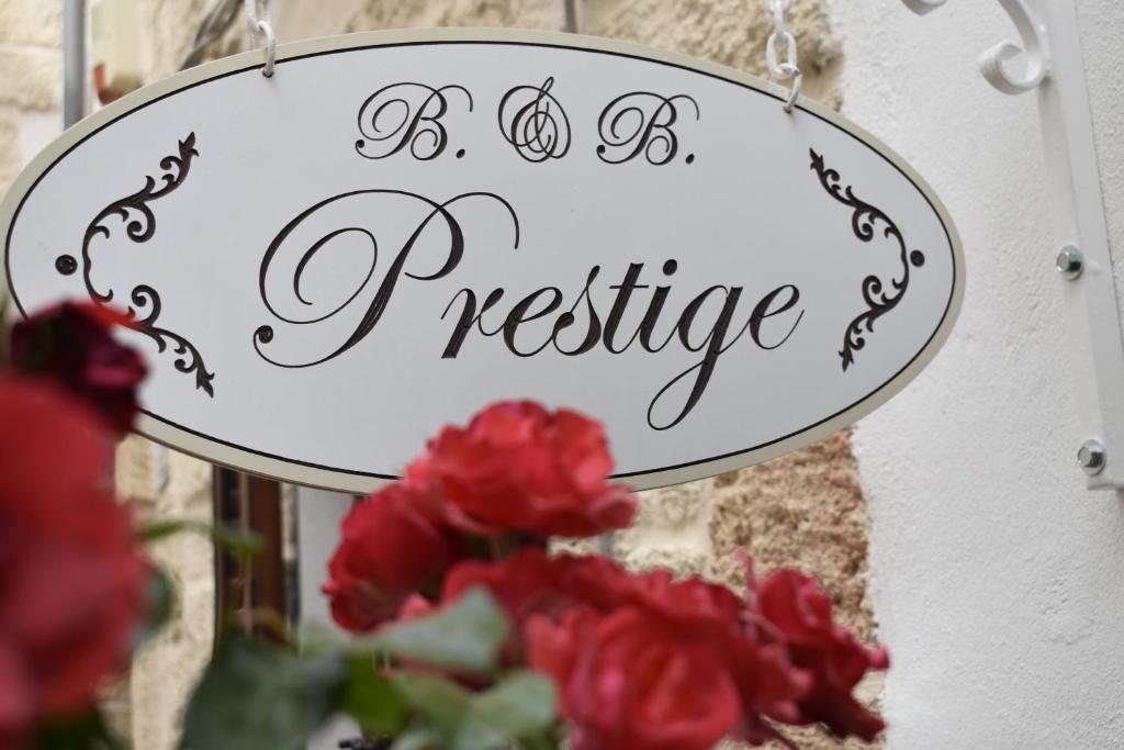 ein Zeichen, das Prestige neben roten Blumen liest in der Unterkunft B&B Prestige in Polignano a Mare