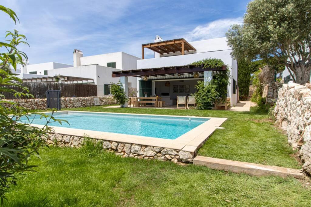 a villa with a swimming pool in front of a house at Villa Conguitos in Sant Lluis