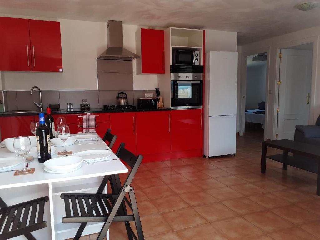 una cocina con armarios rojos y una mesa y sillas blancas. en Casa Rural Los Tres Amigos for holidays and business, en Huércal-Overa