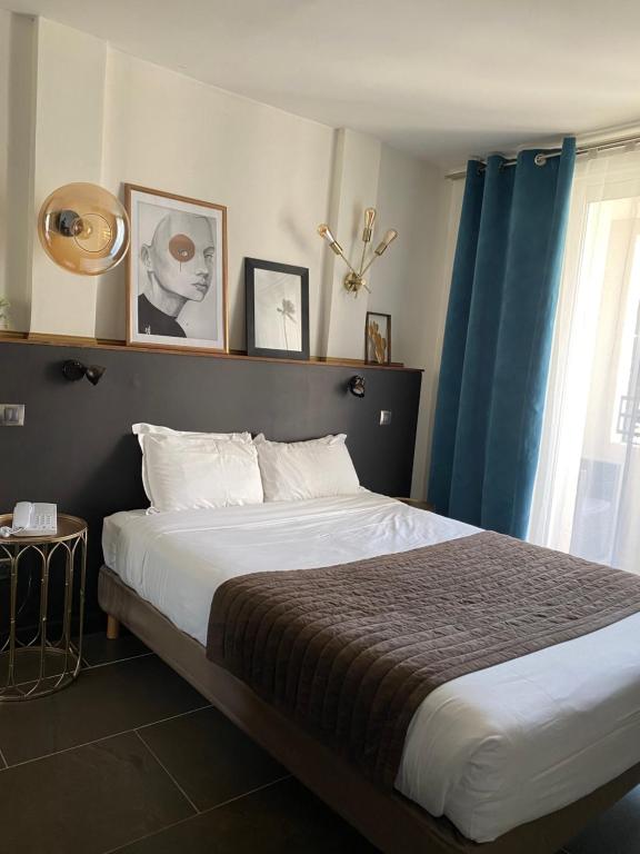 a bedroom with a large bed with a blue curtain at Cors'Hotel in Biguglia