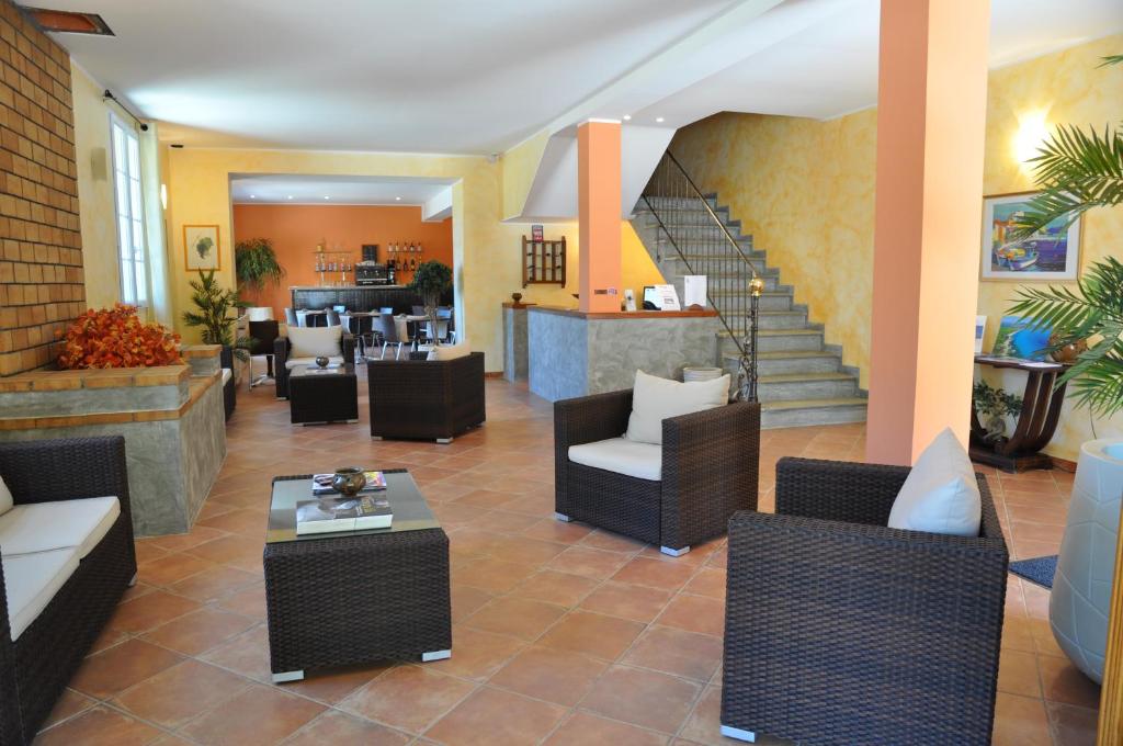 a lobby with chairs and tables and a staircase at Hotel Du Vignoble in Patrimonio