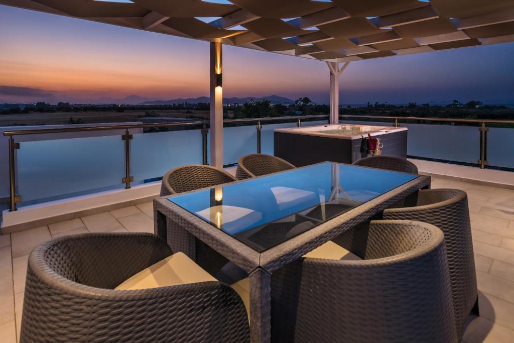 a patio with a glass table and chairs on a roof at ASTERIA PEARL VILLA 2 with Rooftop Jacuzzi in Tigaki