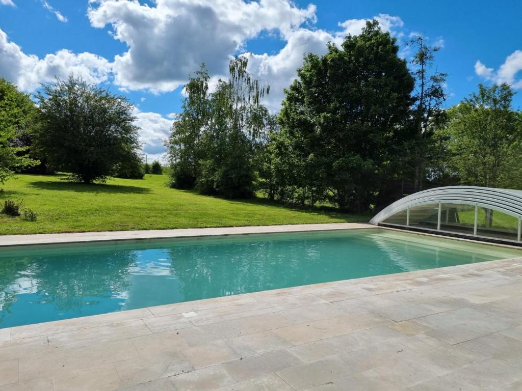 a swimming pool in a yard with a building at Chambres et table d'hôtes Ancienne Poterie in Saint-Martin-des-Champs