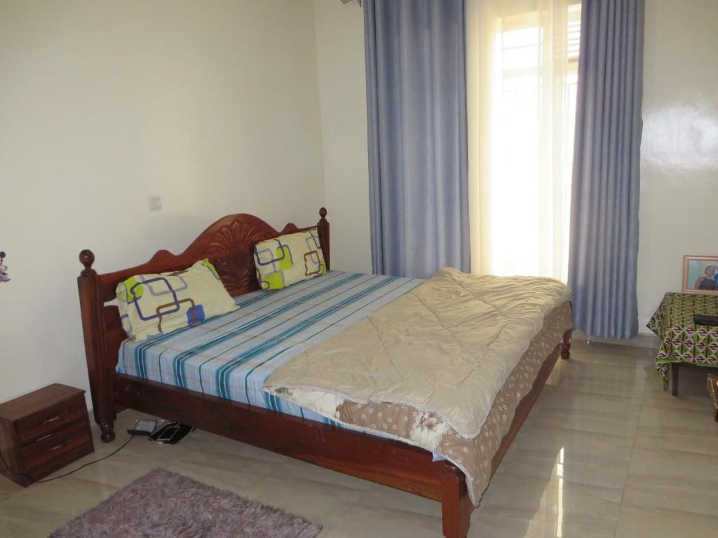 um quarto com uma cama e uma janela em Rooms in homely atmosphere near airport em Kigali