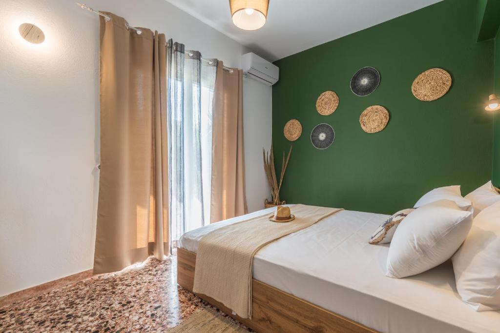 - une chambre avec un mur vert, un lit et une fenêtre dans l'établissement Lazaris Apartments, à Plage d'Almiros