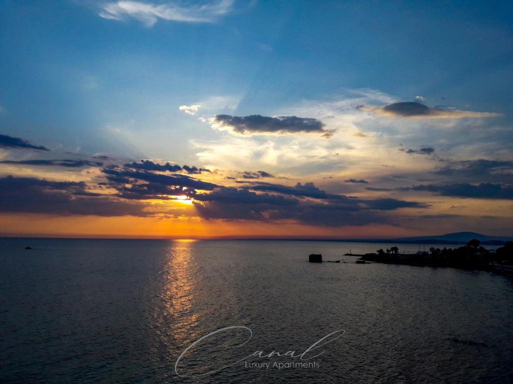 a sunset over a body of water with the sun setting at Canal Luxury Apartments in Nea Potidaea