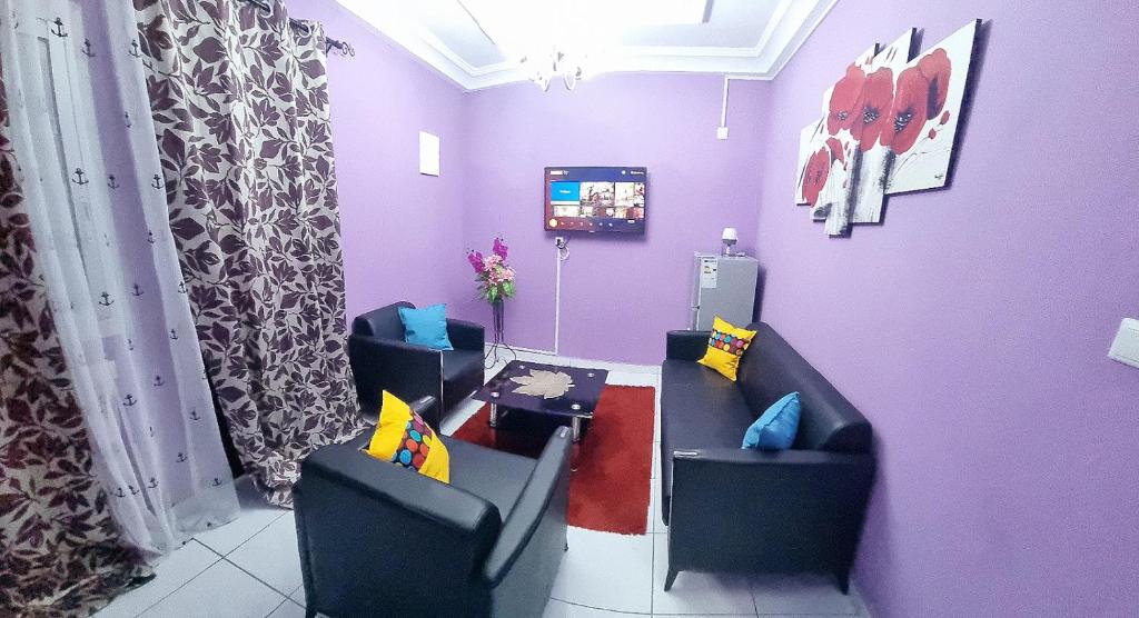 um quarto com duas cadeiras e uma parede roxa em Residence Sighaka - Gold Apartment - WiFi, Gardien, Parking em Douala
