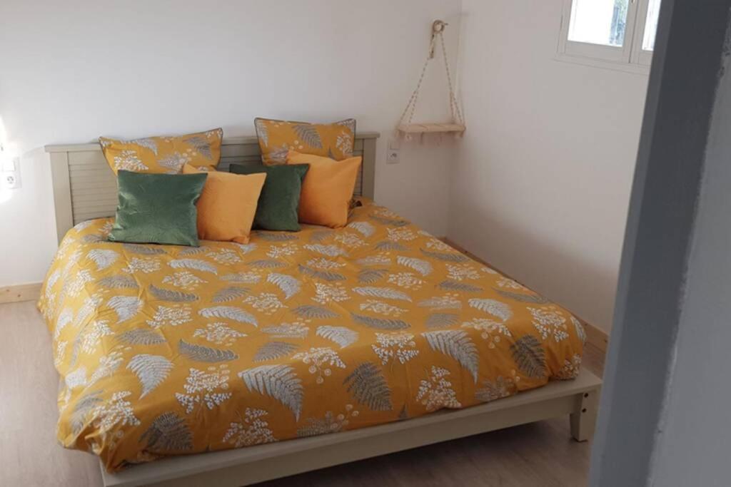 a bed with an orange comforter and some pillows at Appartement dans le Massif du haut Jura in Dortan