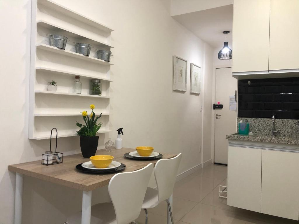 a kitchen with a wooden table and white chairs at Flat Granja Viana - espaço e conforto in Cotia