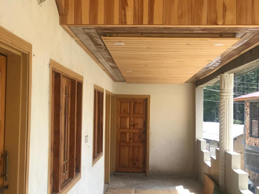 un corridoio vuoto con soffitto in legno e porta di ViveGee Cottage Khanipur Ayubia a Ayubia