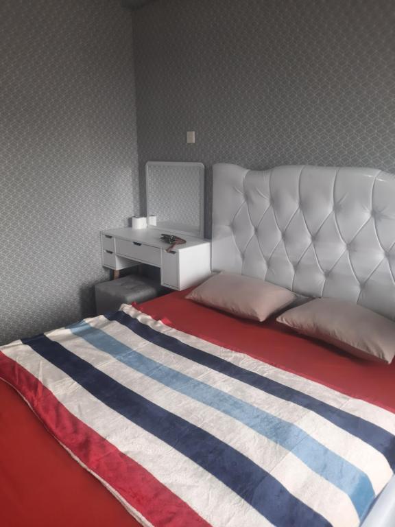 Schlafzimmer mit einem Bett mit einem weißen Kopfteil und einem Schreibtisch in der Unterkunft Apartement emerald bintaro 2 in Pondokaren