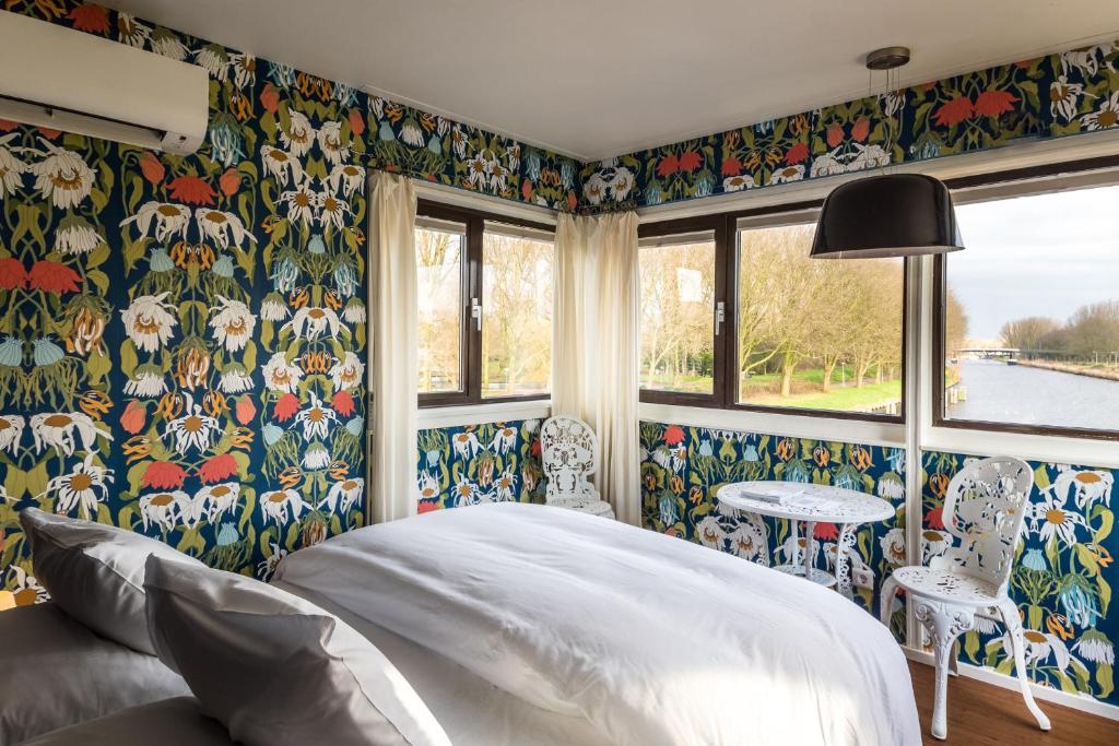 Un dormitorio con una cama grande y papel tapiz floral. en SWEETS - Meeuwenpleinbrug, en Ámsterdam