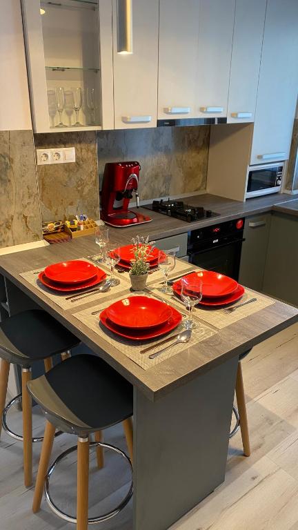a kitchen table with red plates and glasses on it at Katy Boulevard Apartman in Satu Mare